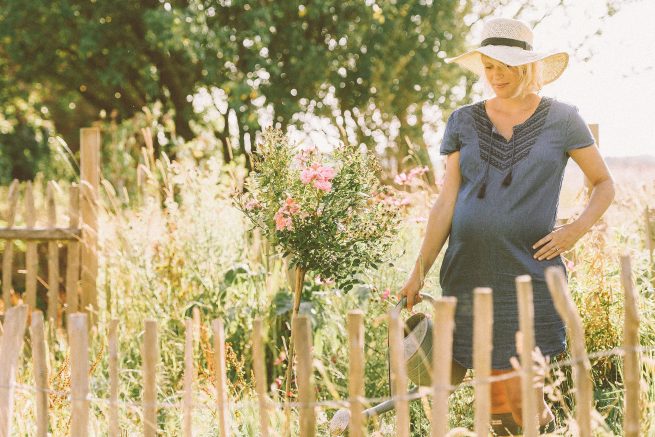 Schwangerschaftsfotografie bei der Gartenarbeit.